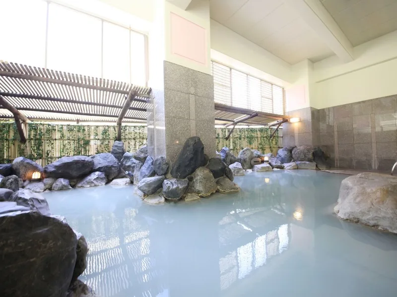 Rock-lined outdoor onsen bath surrounded by greenery at a Noboribetsu Onsen hotel near Noboribetsu Bear Park, Hokkaido